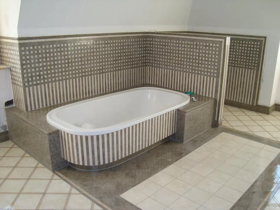 Eingeflieste Badewanne mit Mosaik und gemustertem Fliesenboden